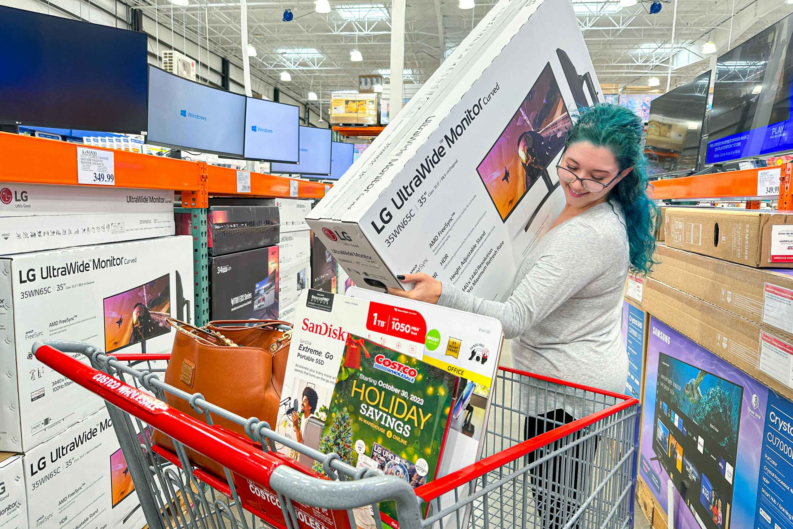 a woman putting a large lg monitor being put in a costco cart
