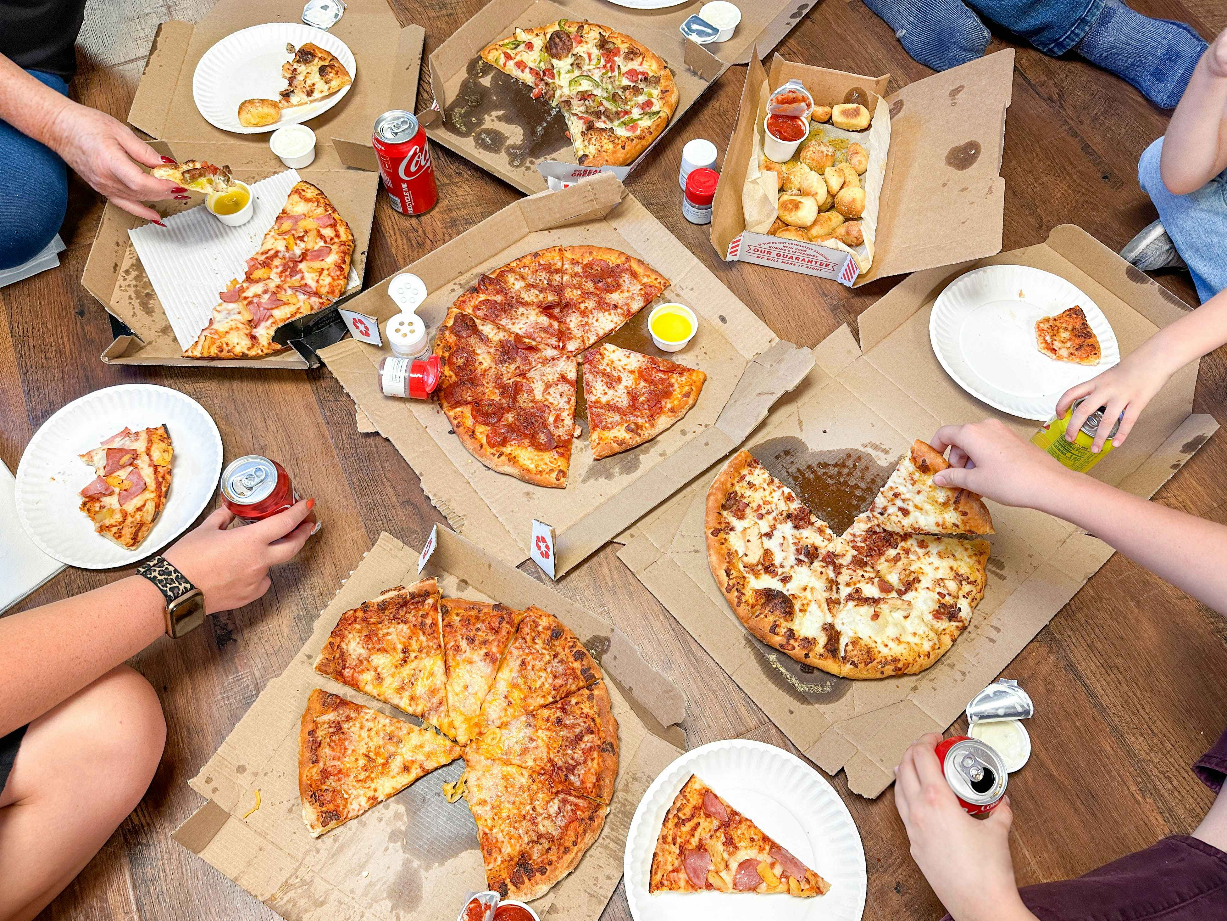 a large pizza dinner with drinks and plates on the floor