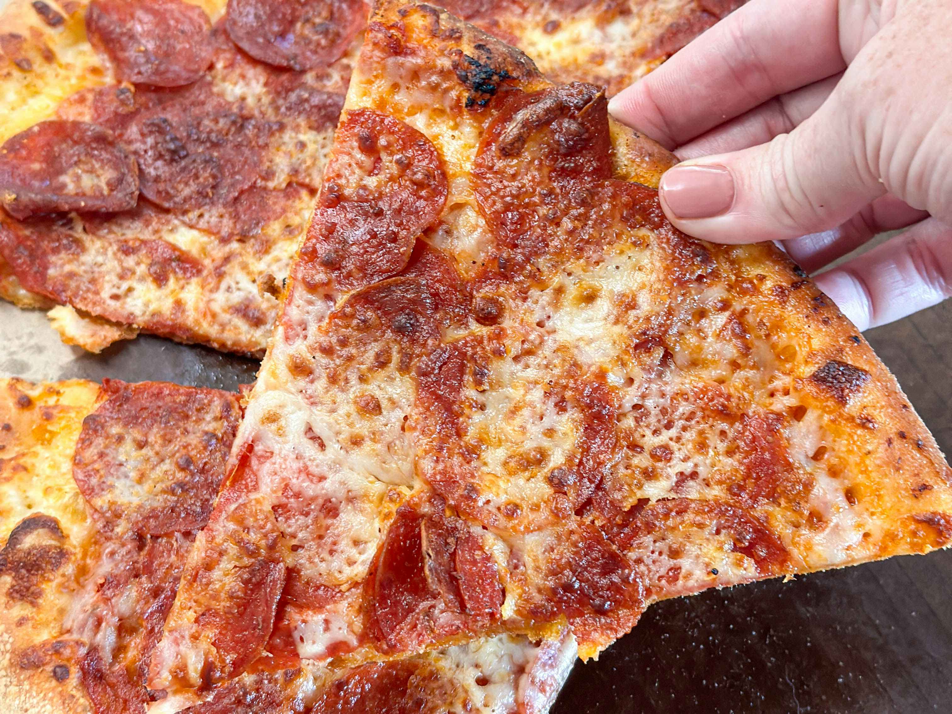 a close up of a person holding a pepperoni pizza