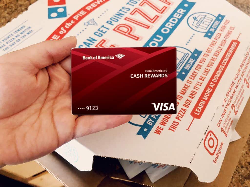 a credit card being held infront of a pizza box 