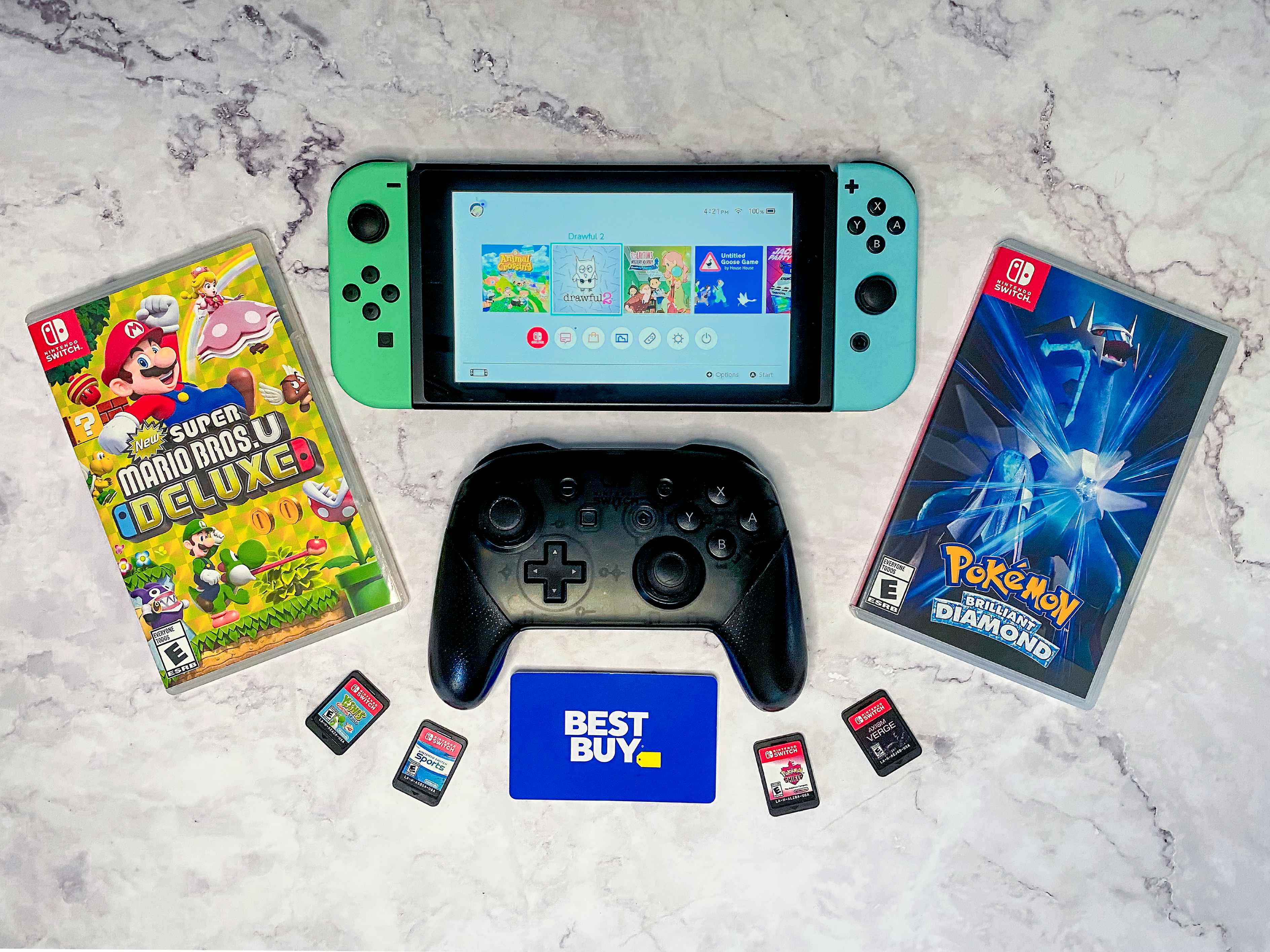 a Nintendo Switch, pro controller, games, and a Best Buy gift card on a table