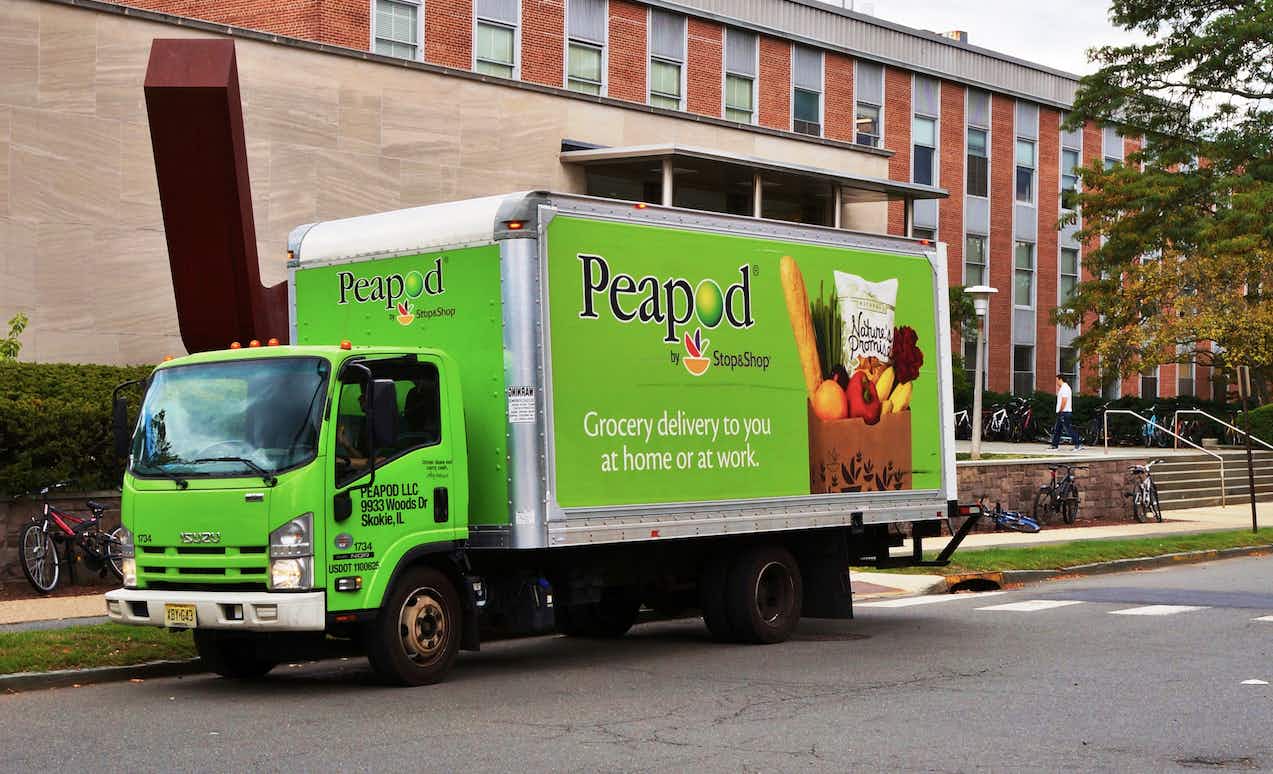 A Peapod food delivery truck parked in front of a building.