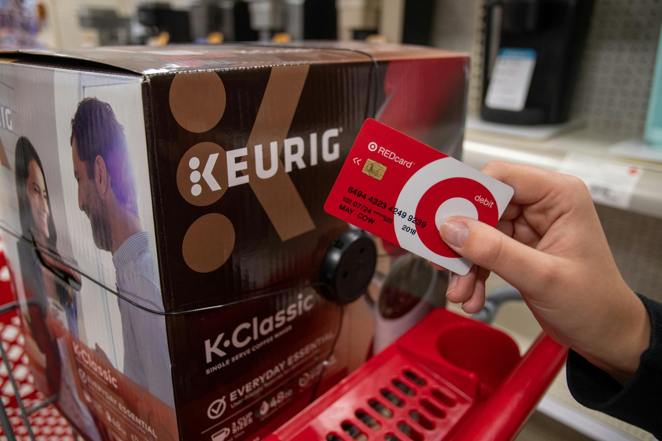 Target red card held next to a Keurig coffee maker inside Target.