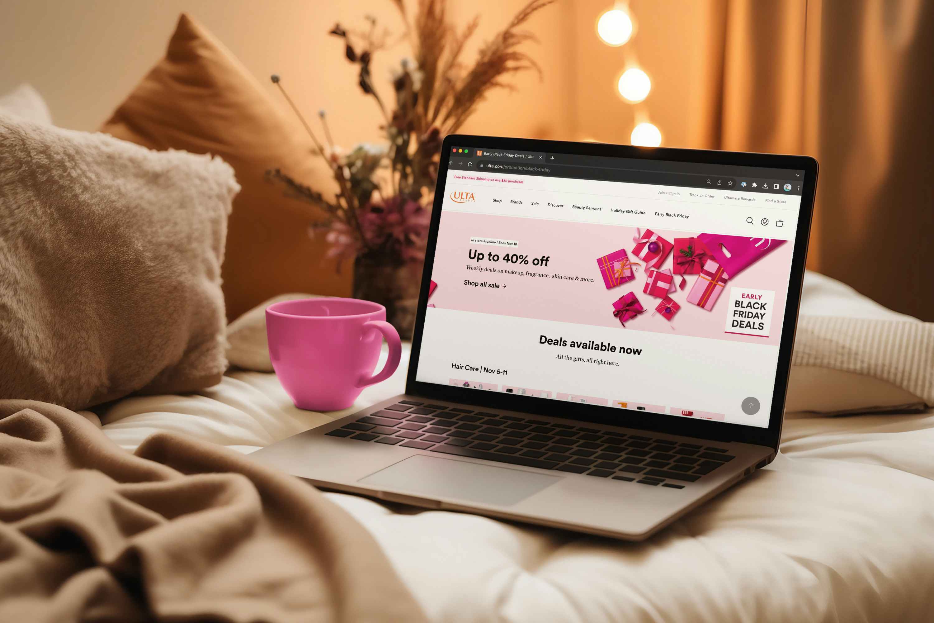 a laptop on a cozy bed, displaying the Ulta early black friday deals webpage