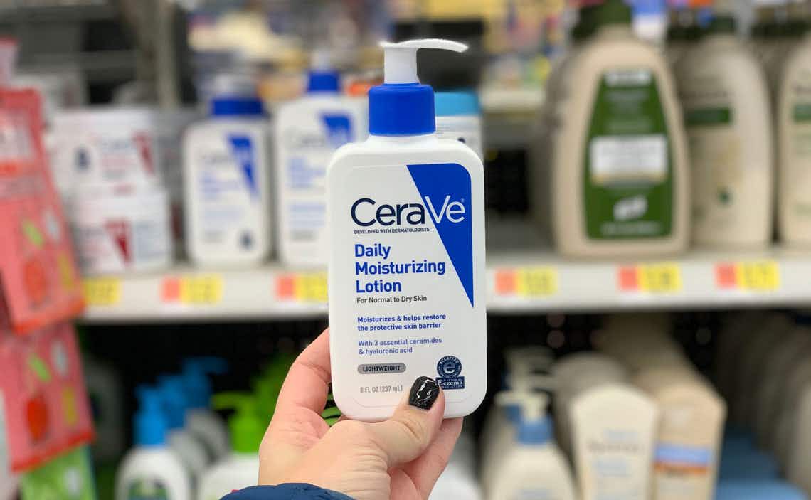 A hand holding a bottle of Cerave lotion in a store aisle.