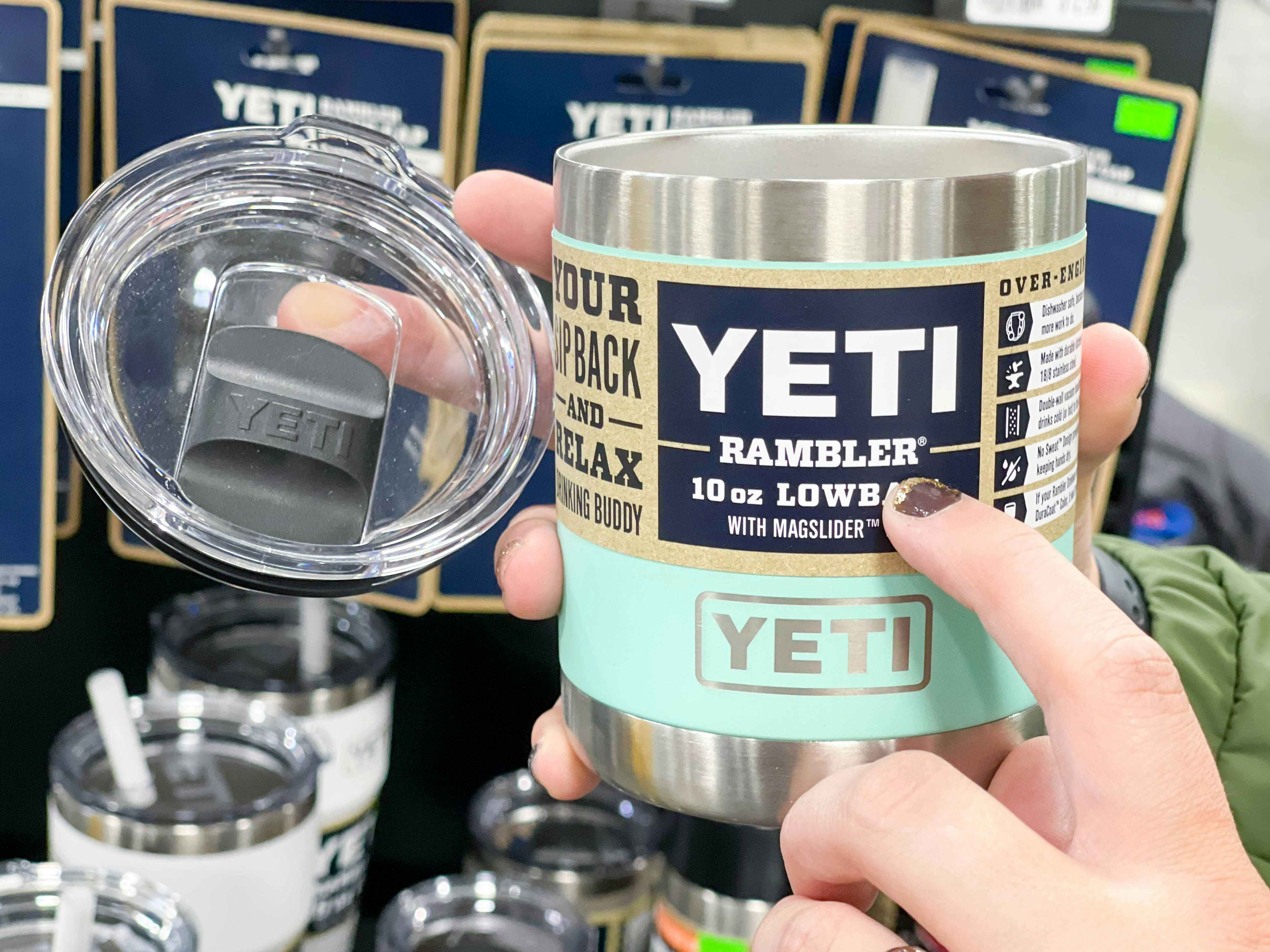 A person's hands holding up a YETI Rambler and lid, and pointing to the product label.