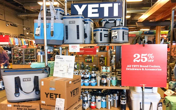 A Yeti display inside REI with a sign advertising 25% off all Yeti coolers, drinkware, and accessories.