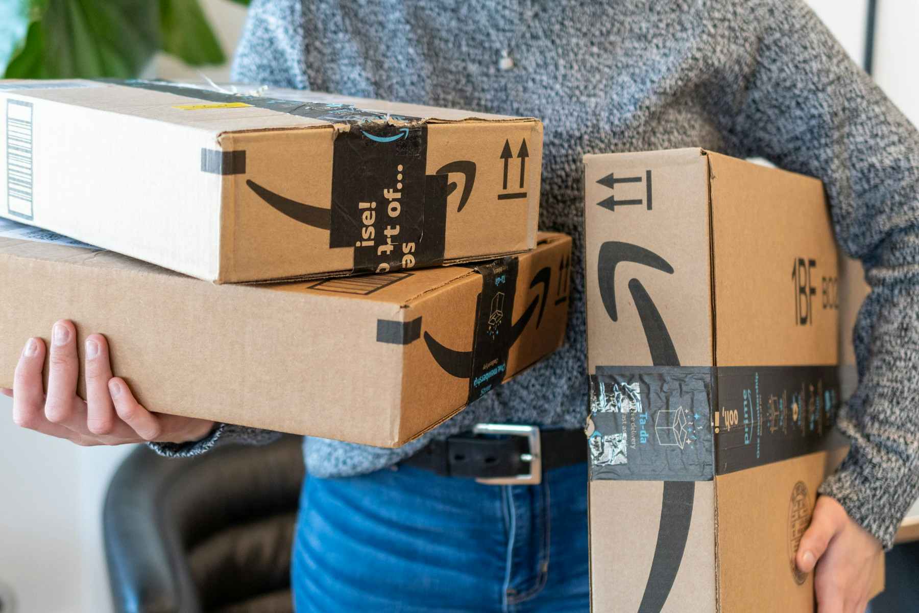 a woman holding 3 amazon boxes