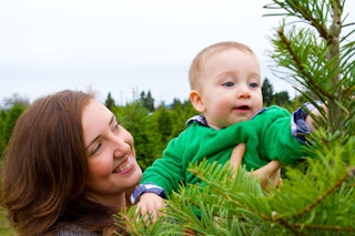 A cute young boy in a green shirt is having fun at a Christmas tree farm in Oregon.
