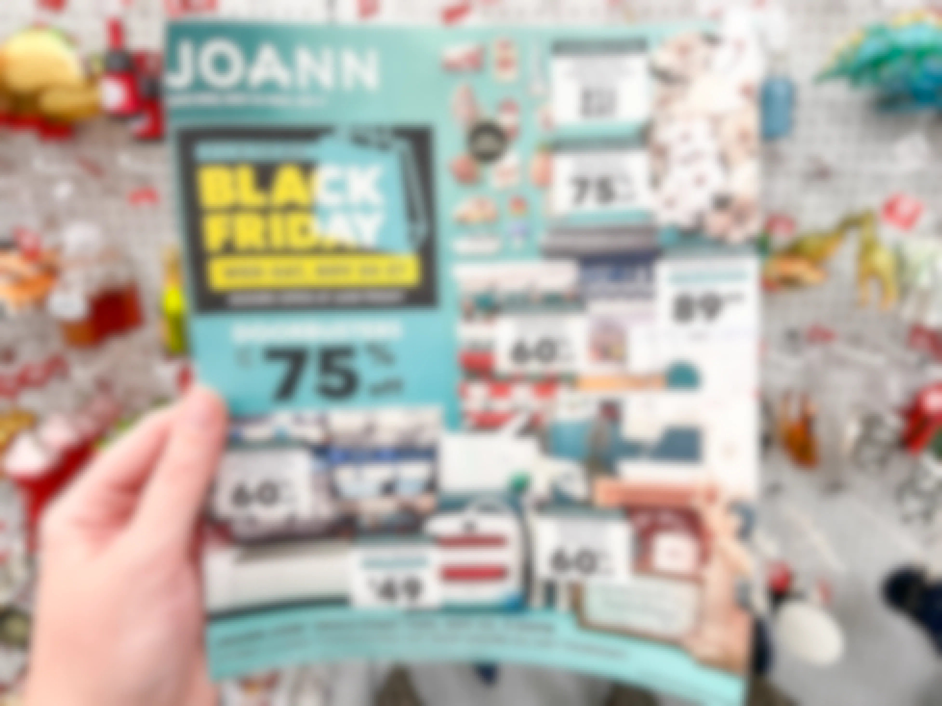 A Joann Black Friday add held in front of Christmas Ornaments.