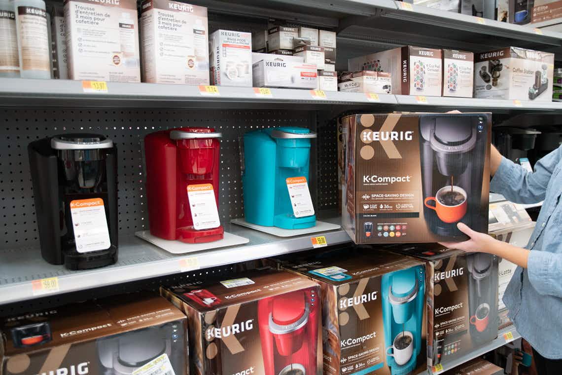 woman holding keurig compact next to keurig section