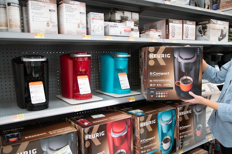 woman holding keurig compact next to keurig section