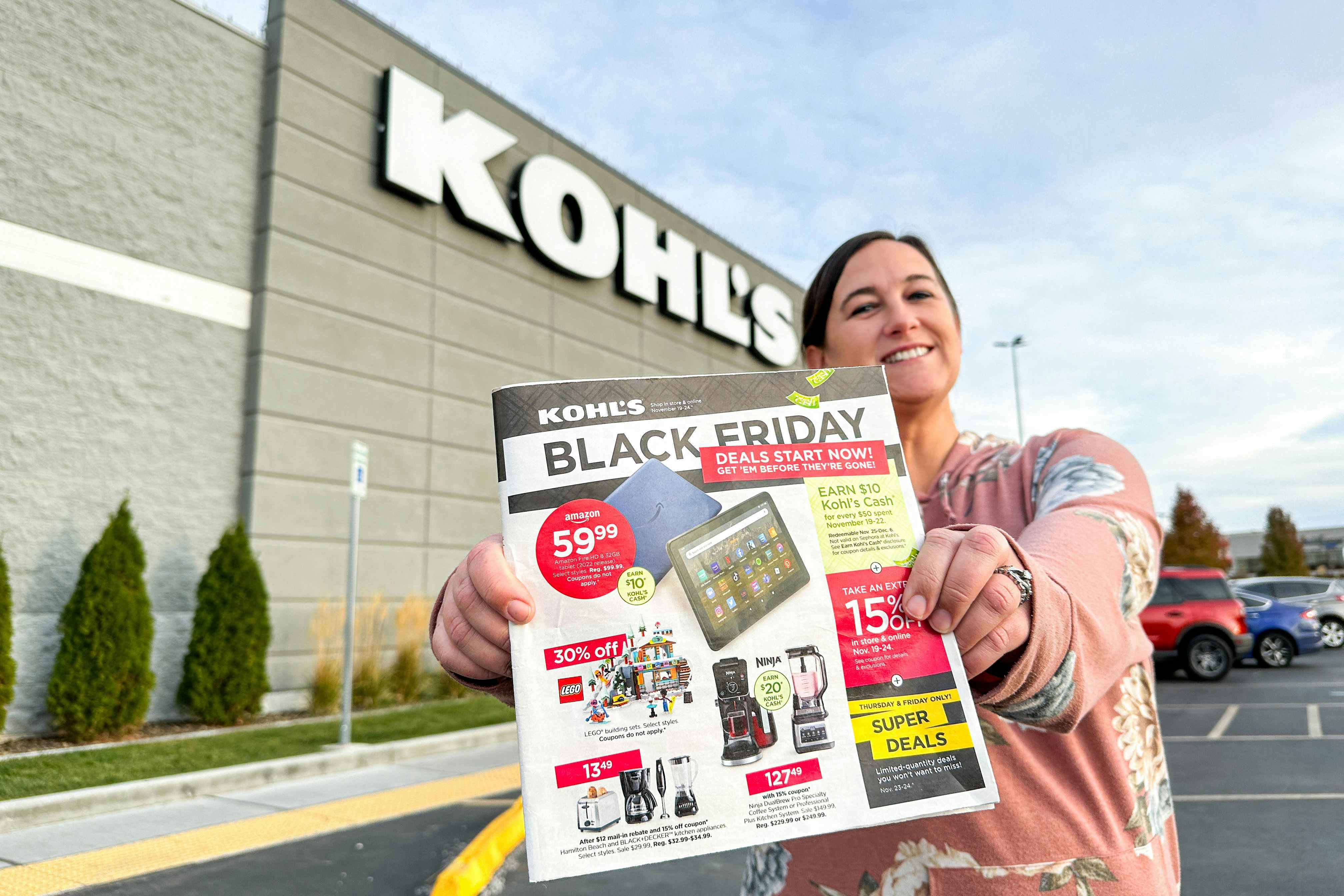 a woman holding the kohls black friday ad outside kohls 