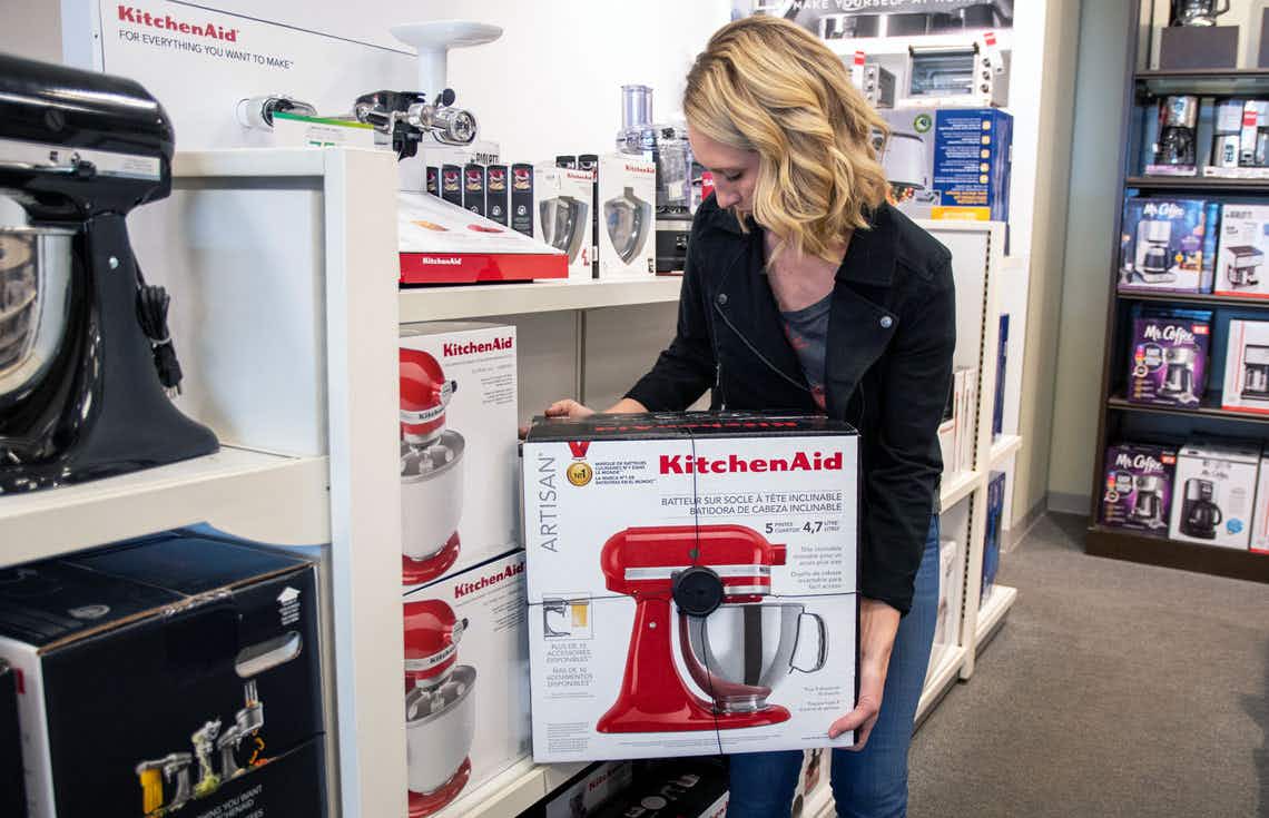 Woman picking up a KitchenAid from a shelf in Kohls