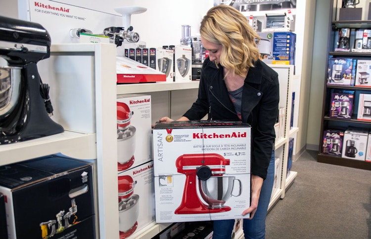Woman picking up a KitchenAid from a shelf in Kohls