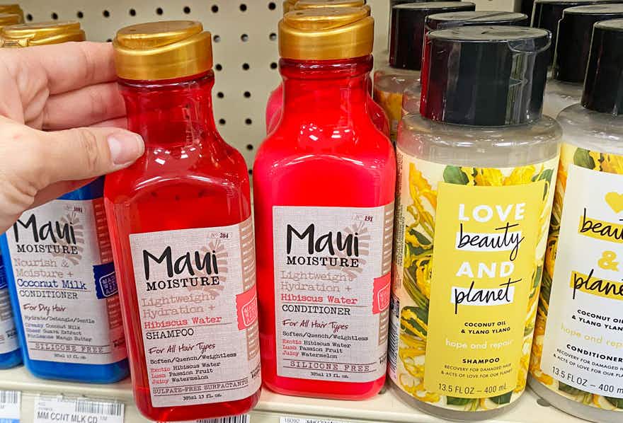 hand picking up bottle of Maui Moisture shampoo on shelf