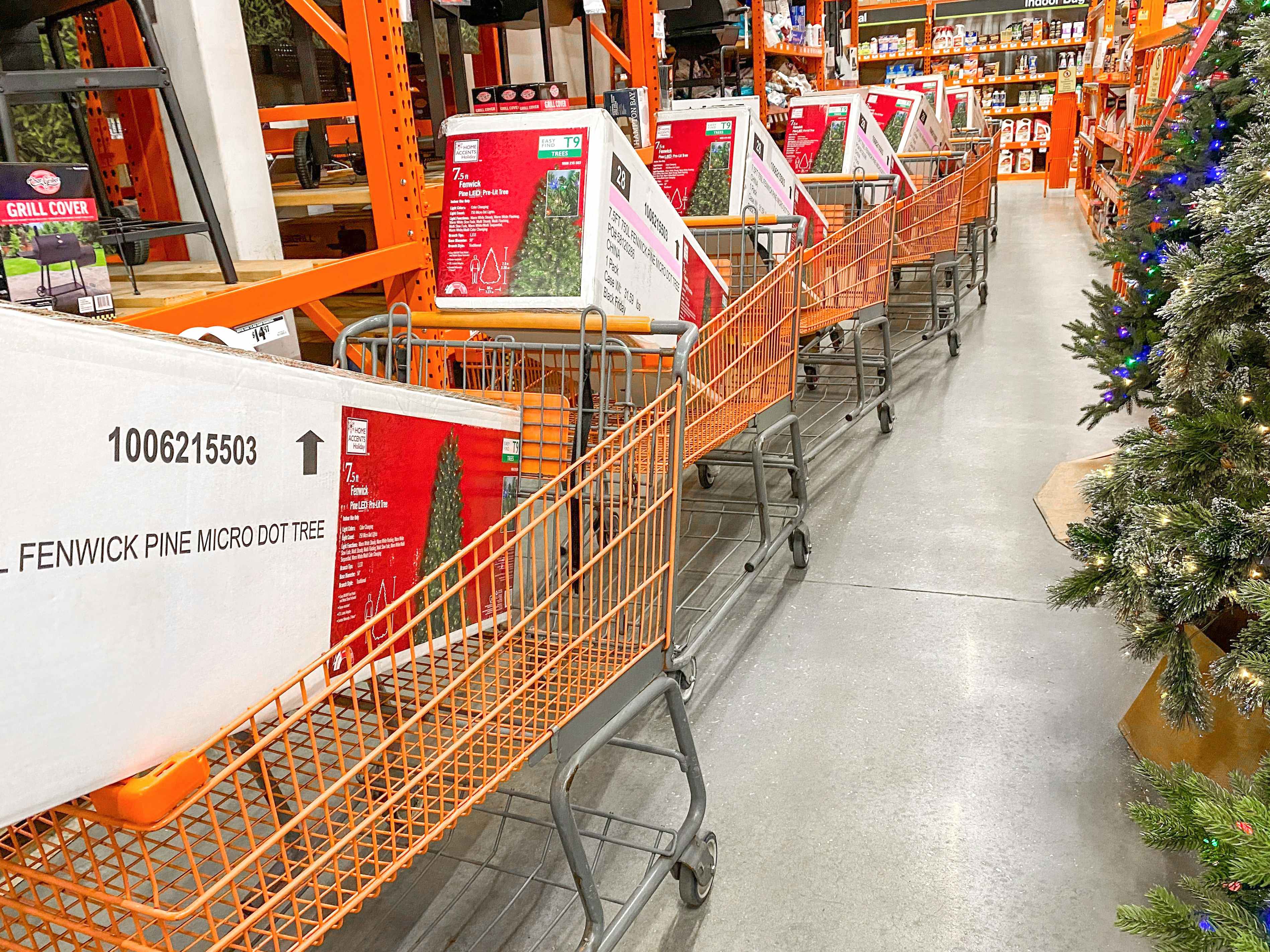 A line of shopping carts filled with boxes of pre-lit artificial Christmas trees at Home Depot.