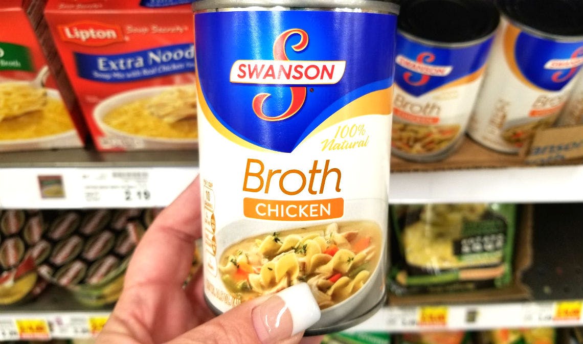 A person holding a can of Swanson broth.