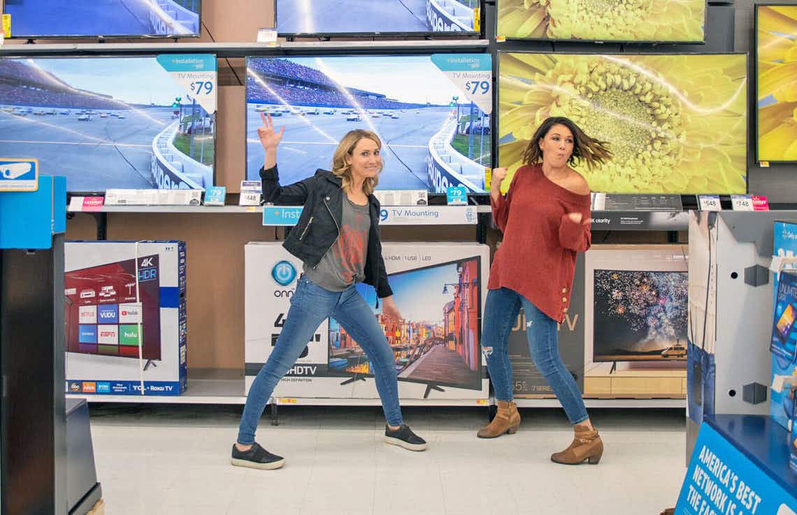 Two women dancing in the TV aisle of Walmart.
