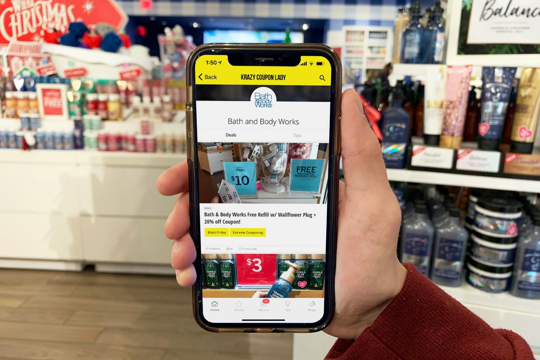 A hand holds a smartphone with the Krazy Coupon Lady app open, showing Bath and Body Works coupons on the screen