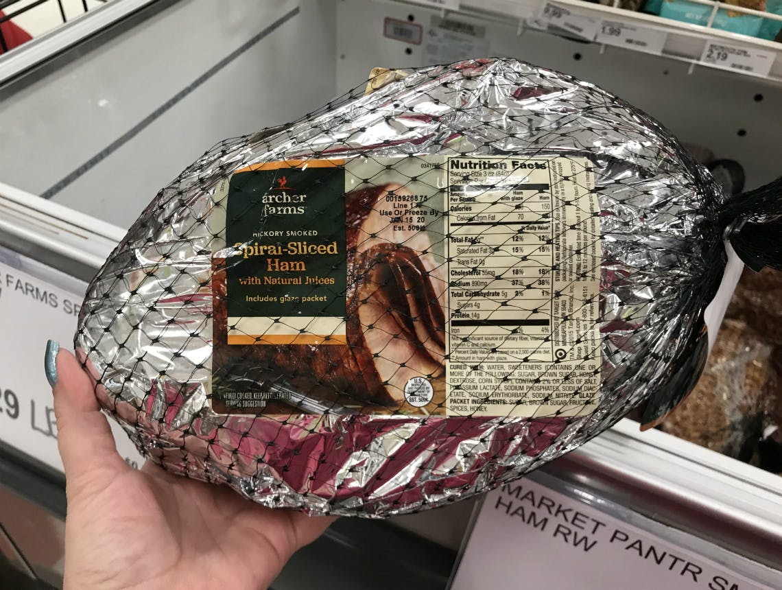 A person holding a packaged ham.