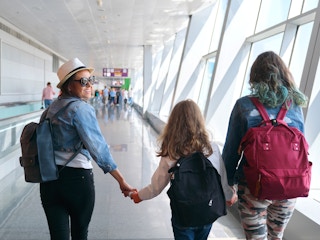 mother and daughters walking in airport terminal