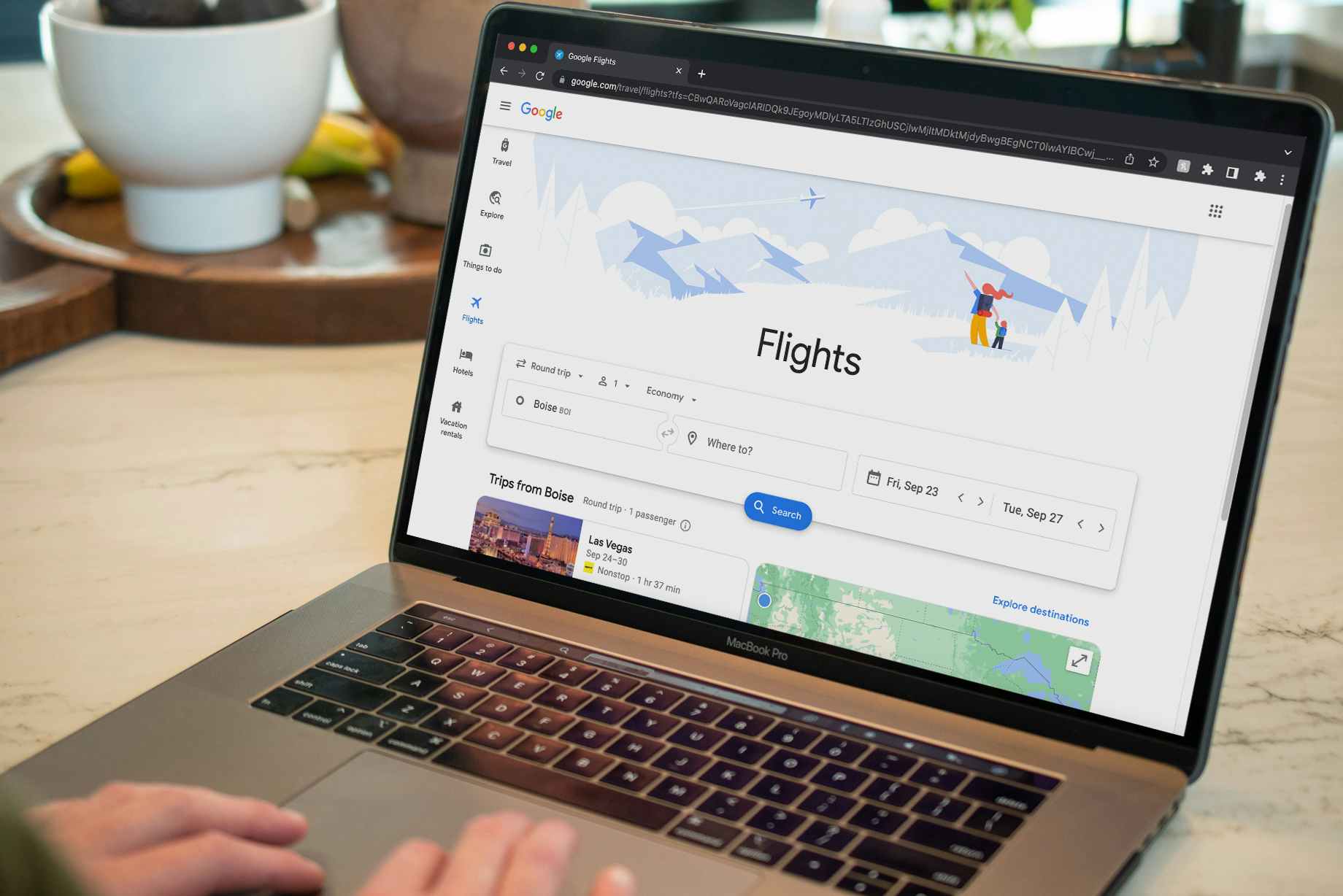 A person using a laptop displaying the Google Flights home page.