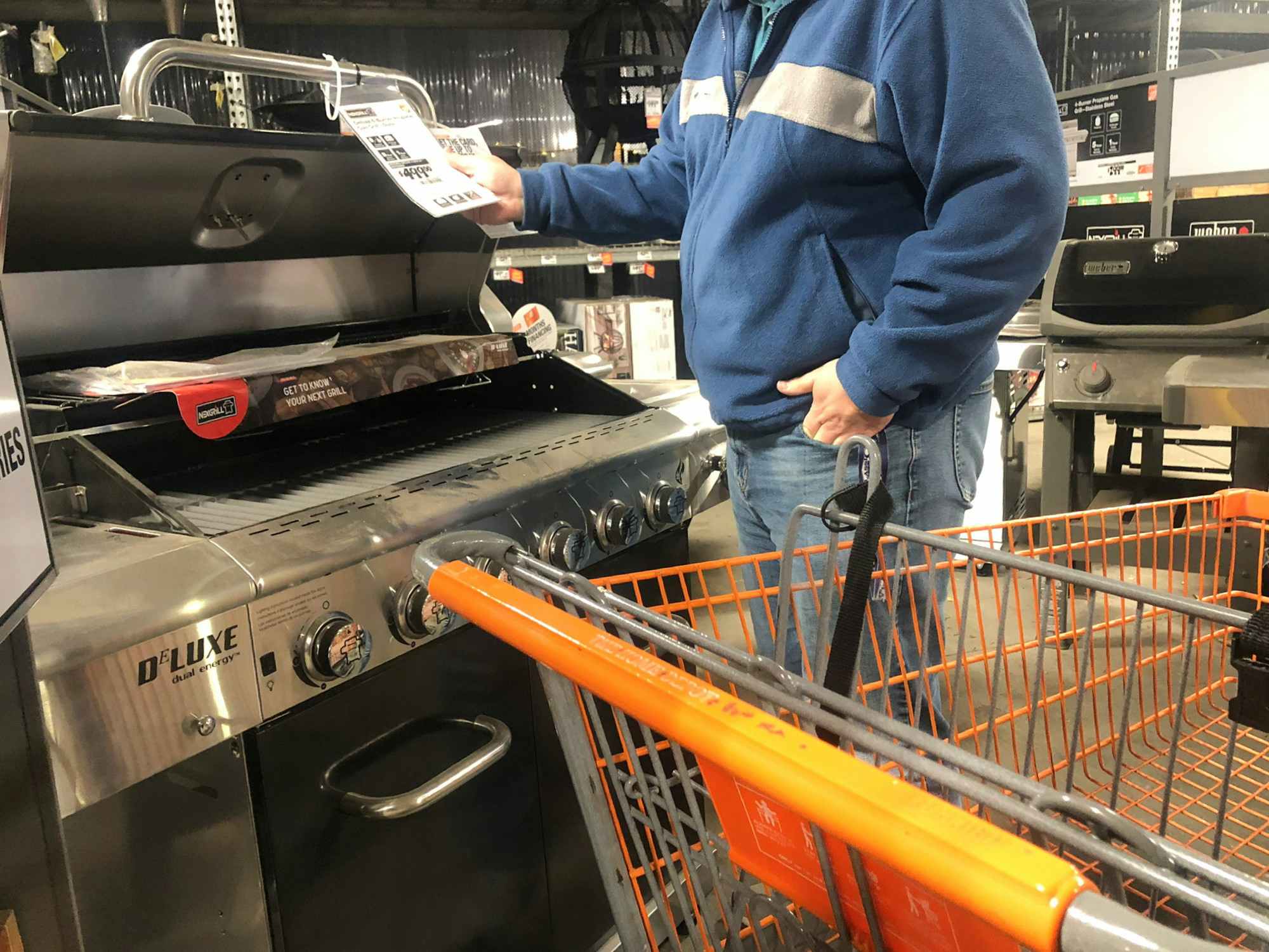 a man looks at the price tag of a grill at Home Depot