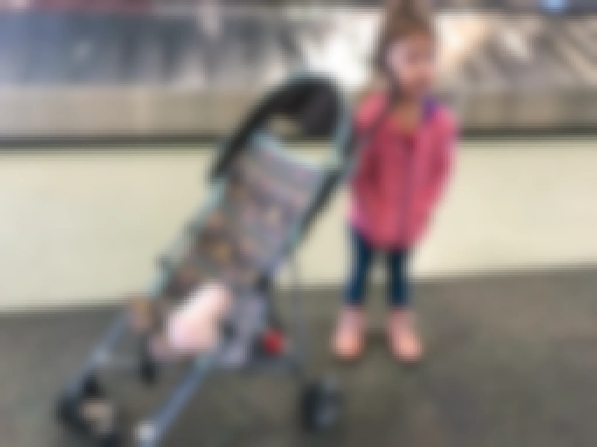 a little girl standing next to a stroller in an airport