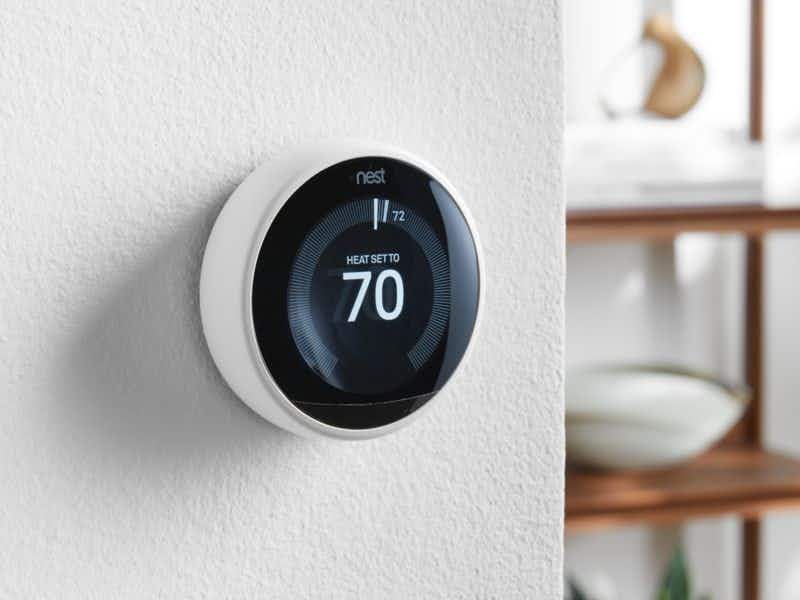 A Nest thermostat on a wall in someone's home, set to 70 degrees Fahrenheit.
