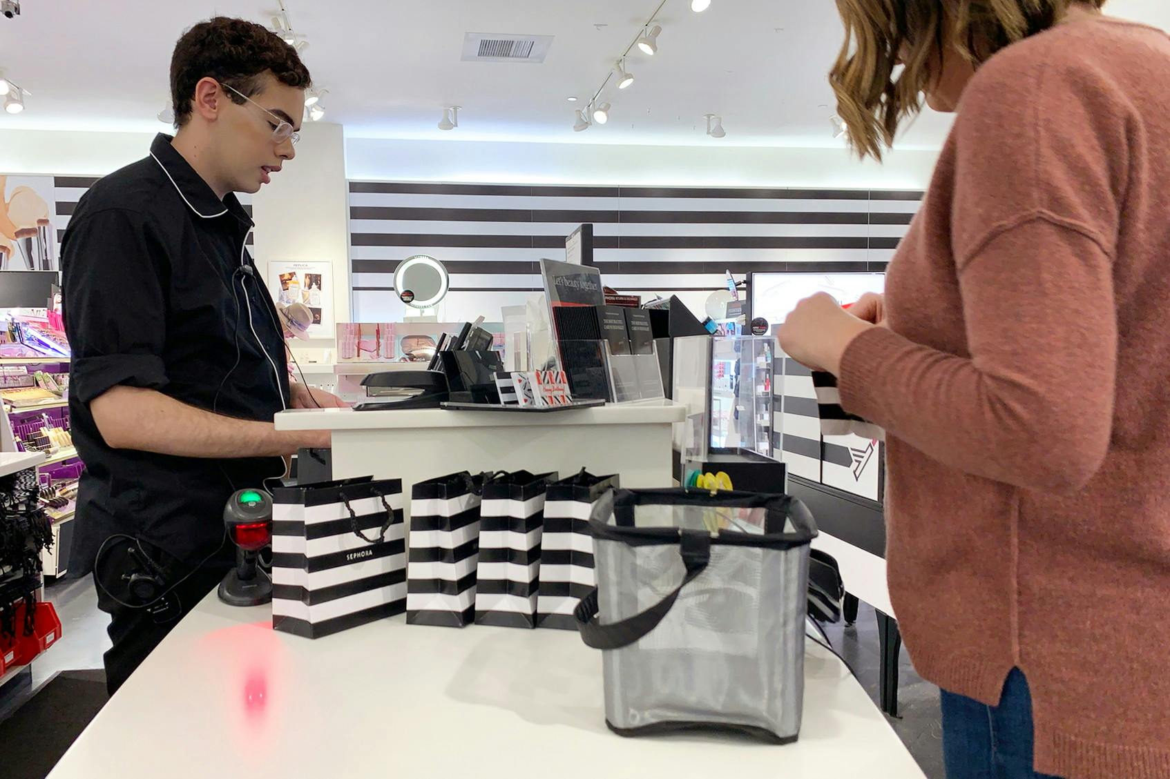 woman standing at sephora counter and a man at checkout with basket on the counter