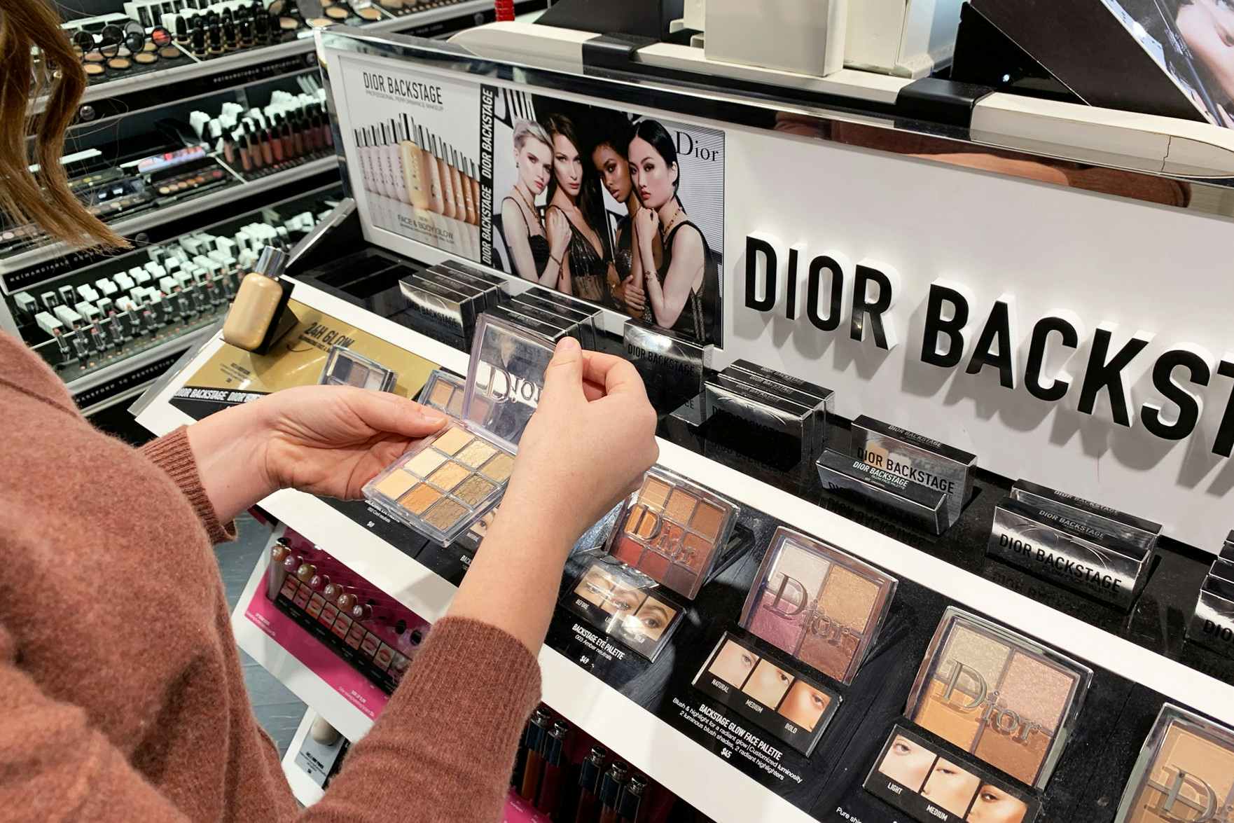 Woman looking at Dior makeup compacts in Sephora. 