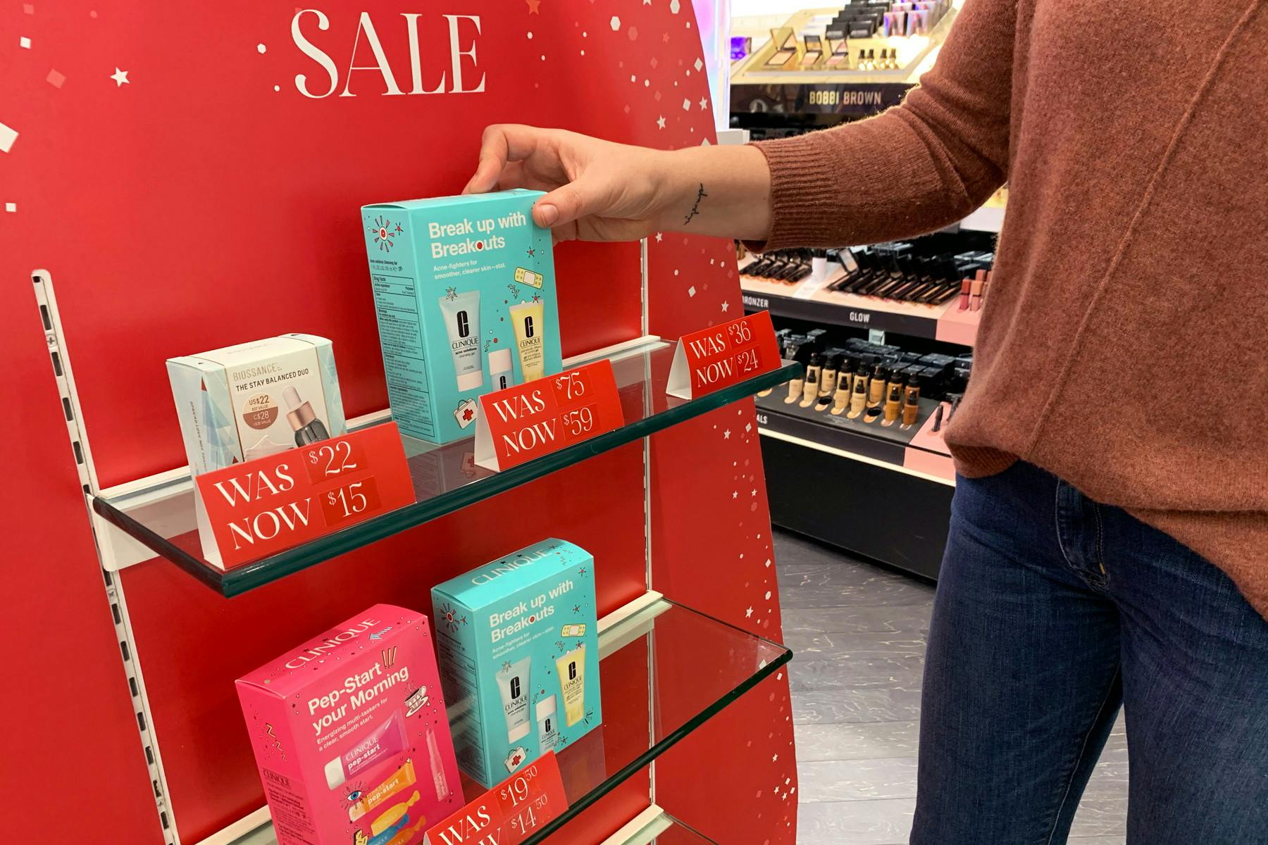 A person reaching to take a product from a sale shelf in Sephora.