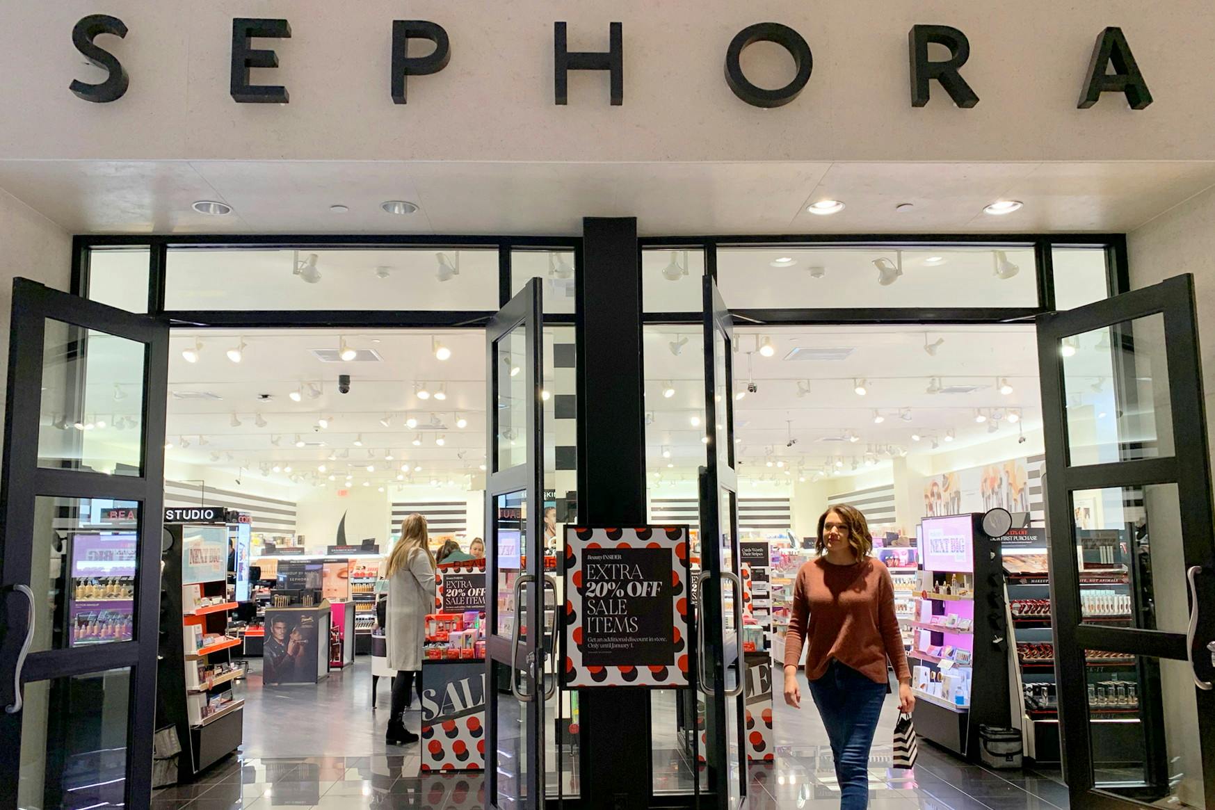 Woman walking out of Sephora store with shopping bag.