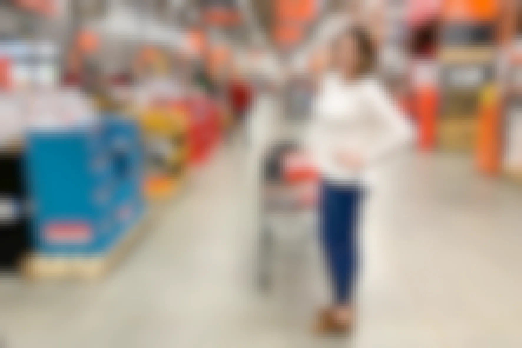 A woman standing and posing with a cart by the checkout lanes at Home Depot