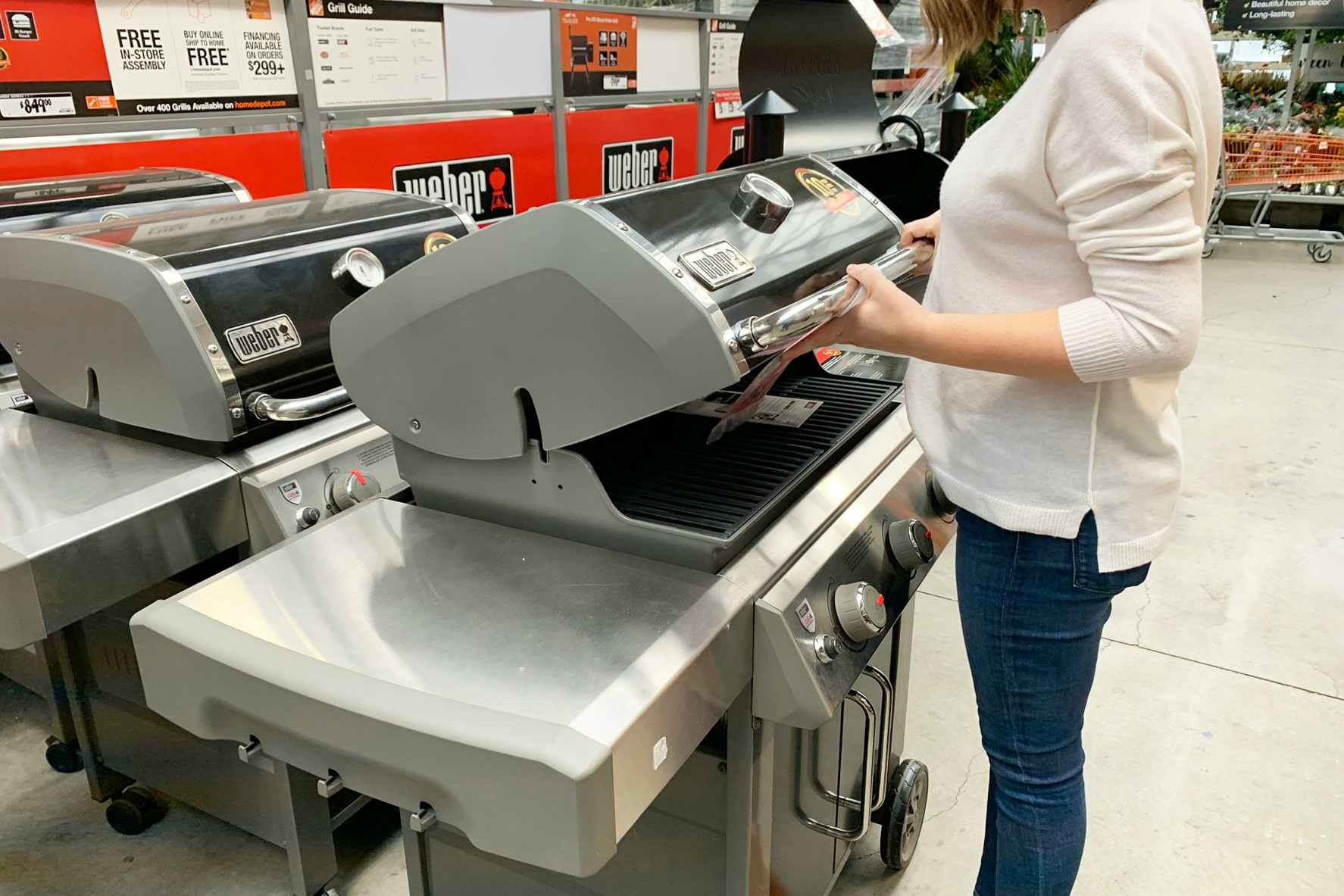 A woman looking at a grill in The Home Depot garden center.