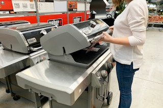 A woman looking at a grill in The Home Depot garden center.