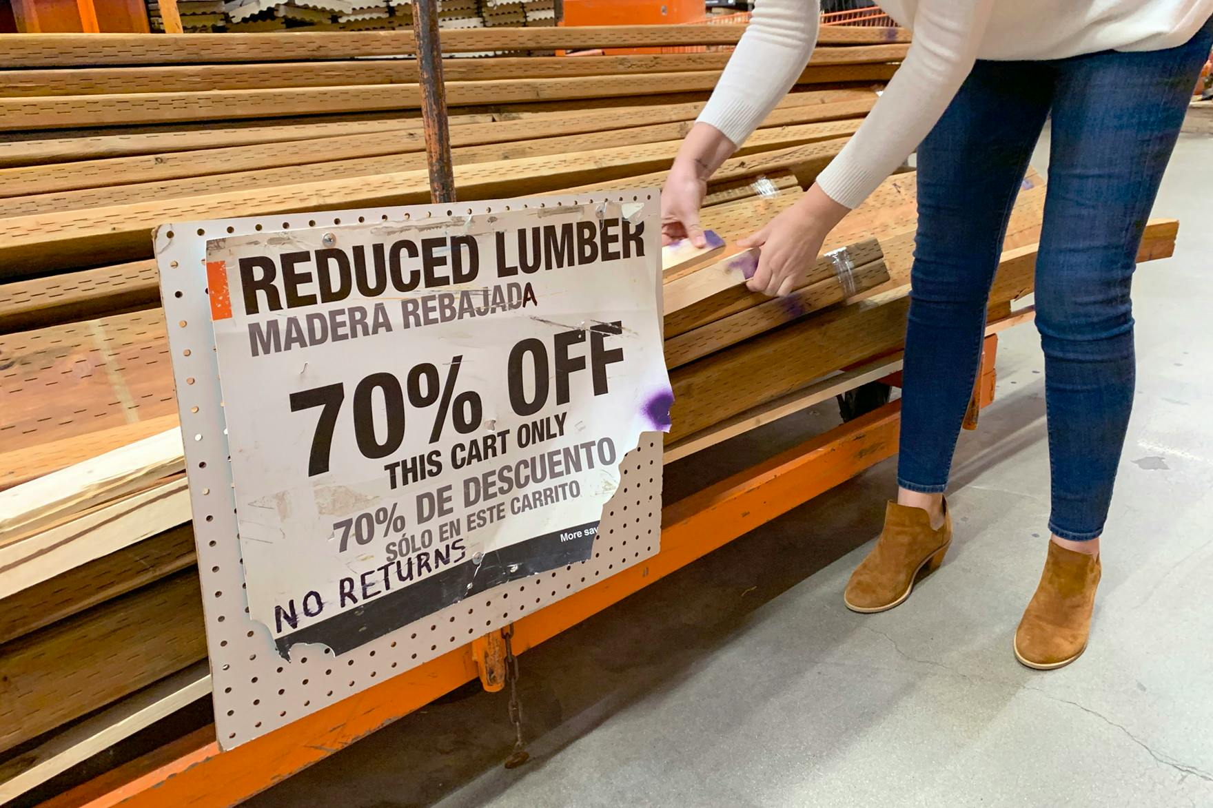 A woman taking wood off the reduced lumber pile.