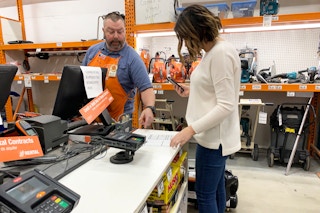 A woman talking to an employee in the tool rental shop at The Home Depot.