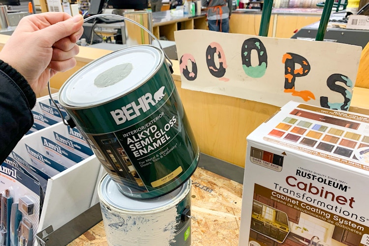 A person holding a gallon can of Behr paint
