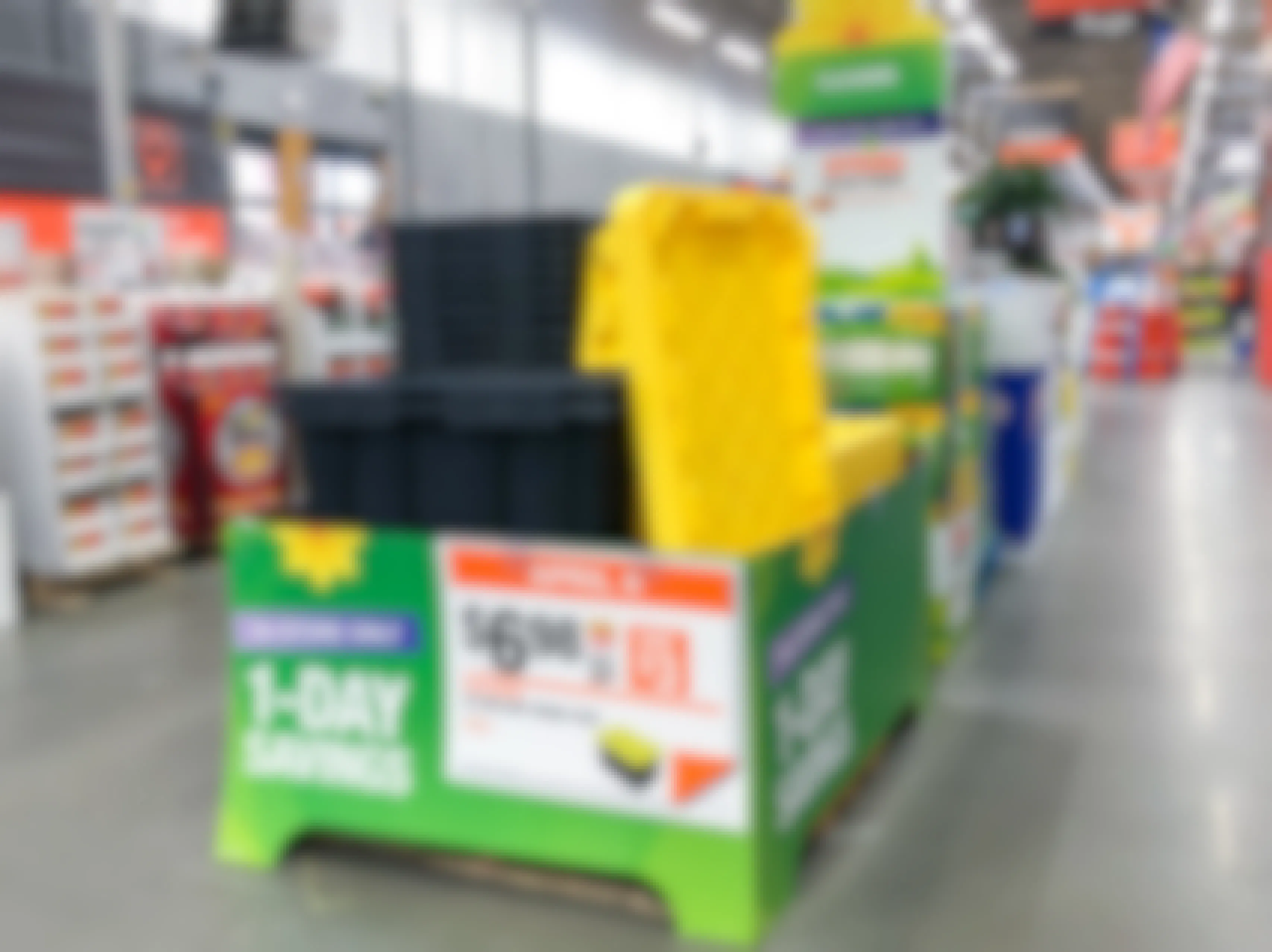 A display of black and yellow storage bins with a 1-day savings sign.
