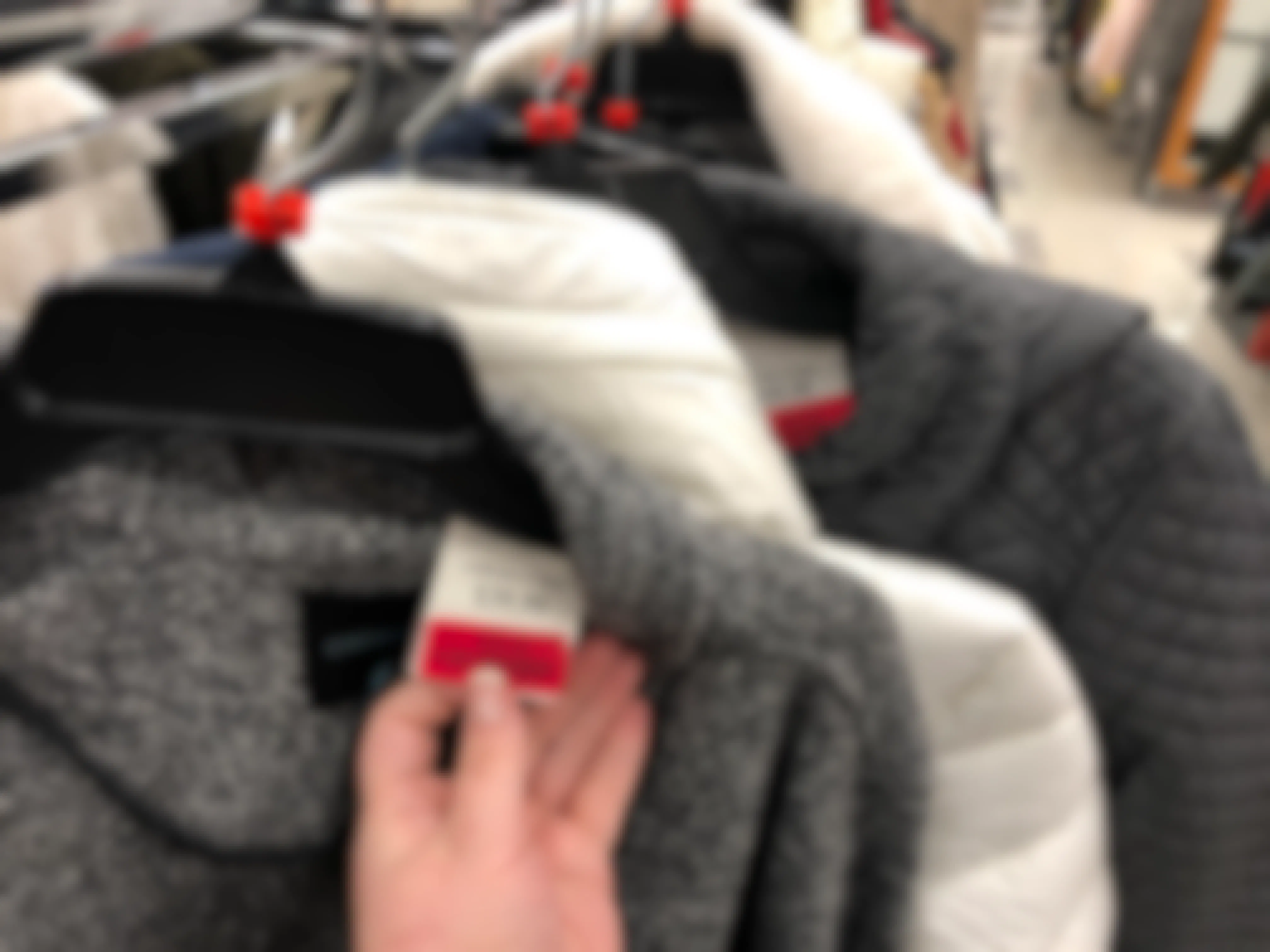 Someone checking the clearance tag on a coat at TJMaxx