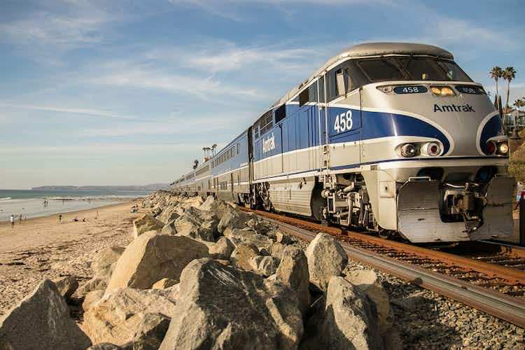 An Amtrak train chugs along a rocky coast