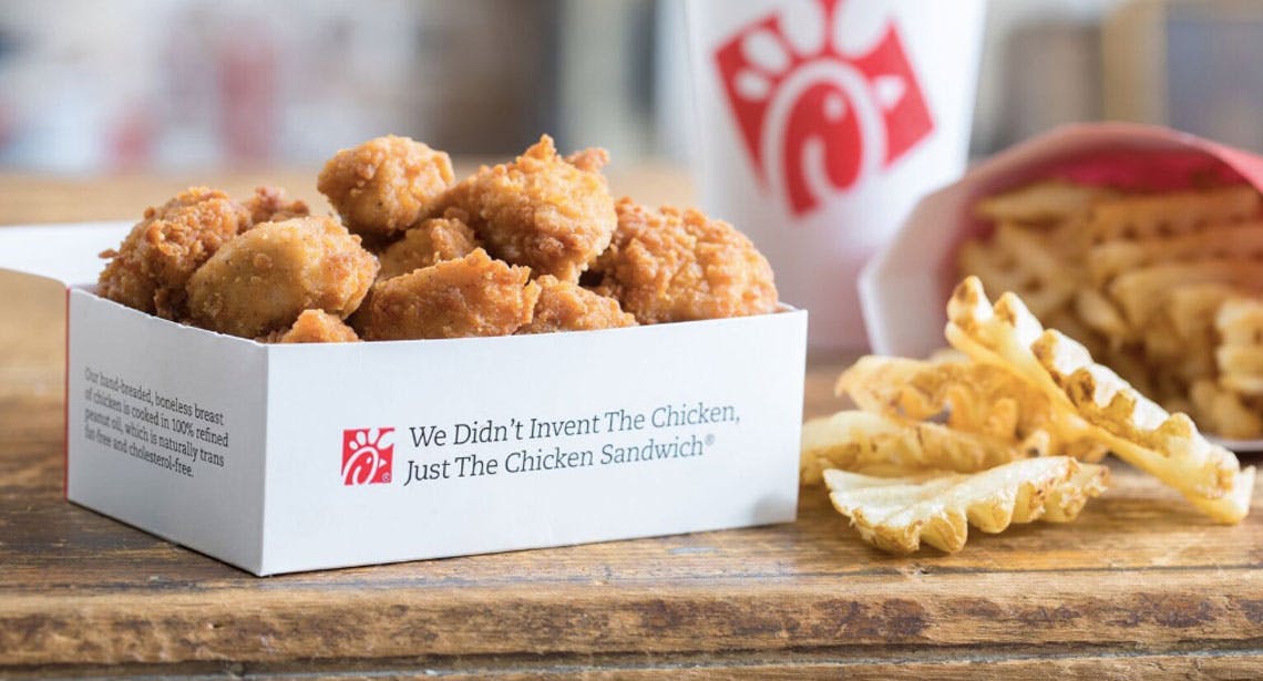 Picture of an 8-count chicken nuggets in a box next to fries and a drink on a table