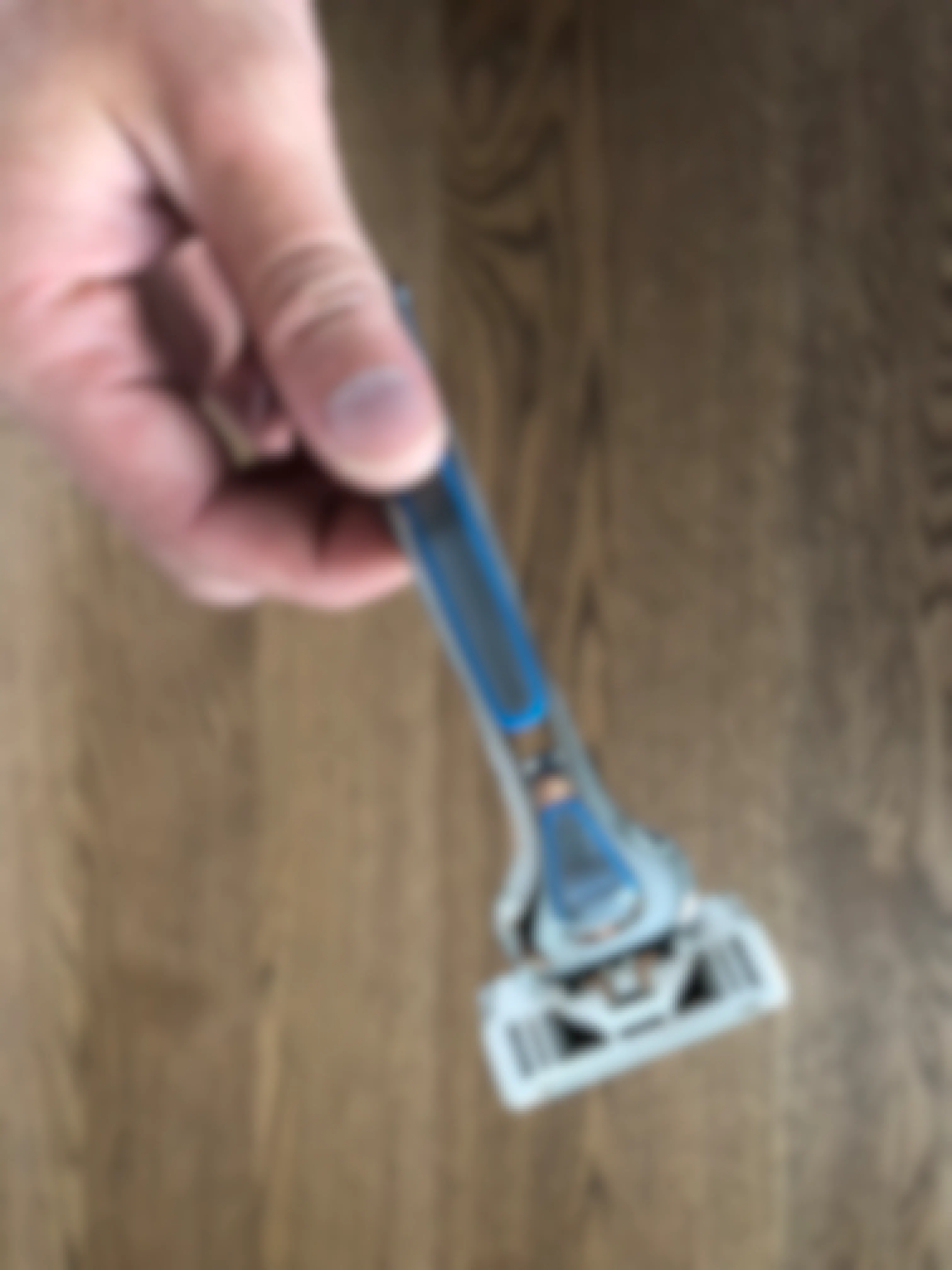 A hand holding the Dollar Shave Club Executive razor with blade.