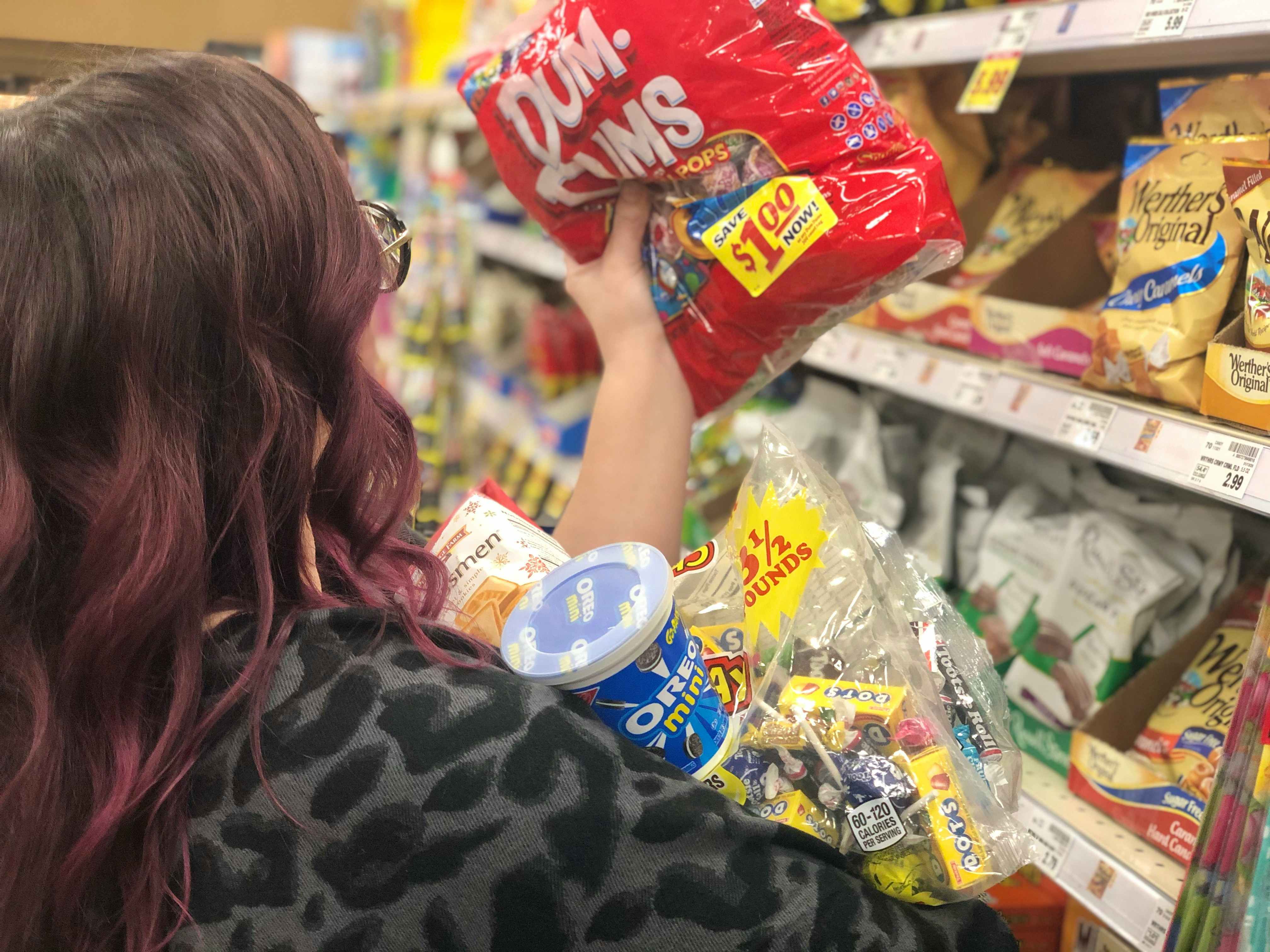 A woman grabs armfuls of candy.