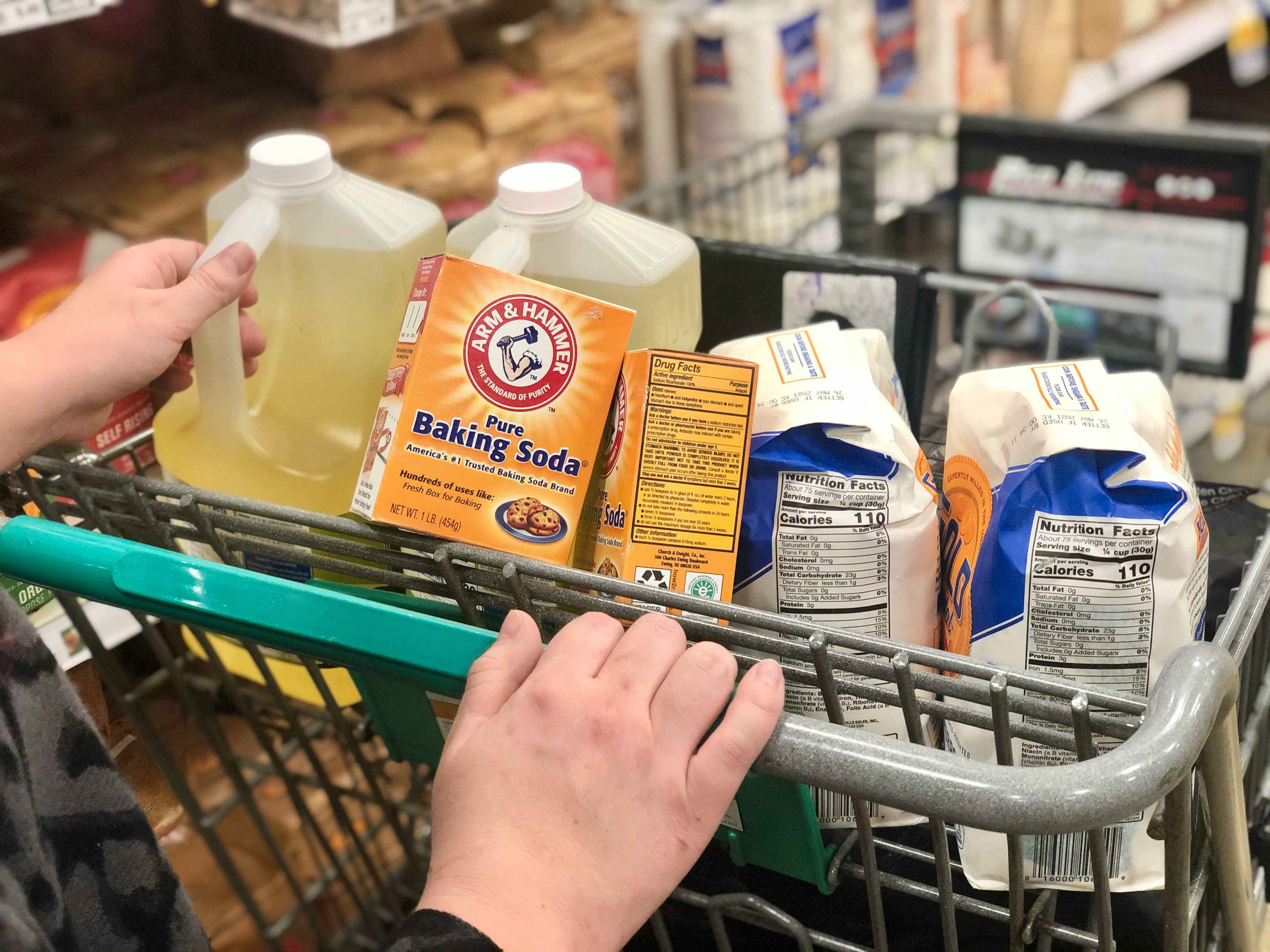 A woman has a cart full of pantry items.