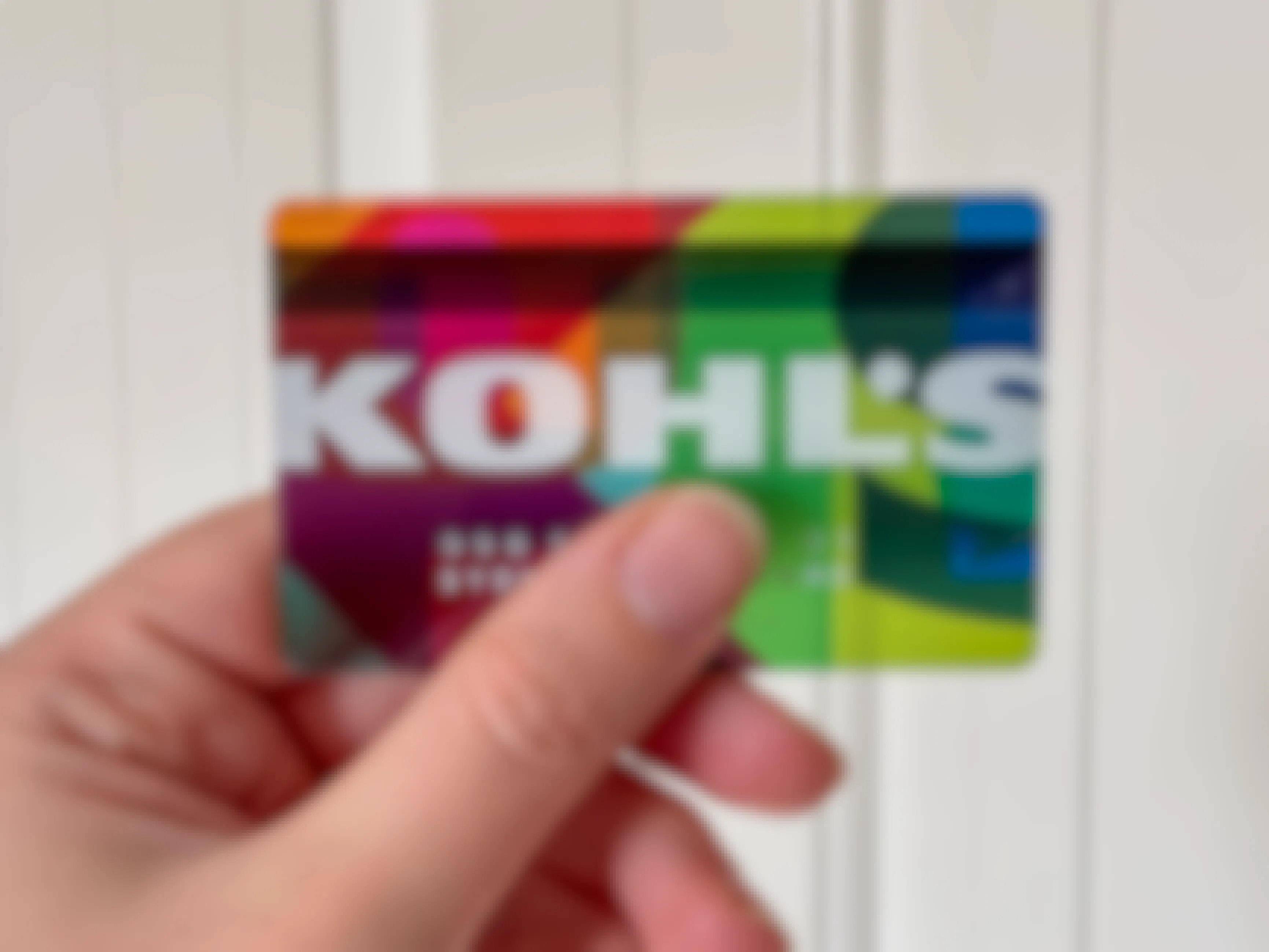A hand holding a Kohl's credit card.