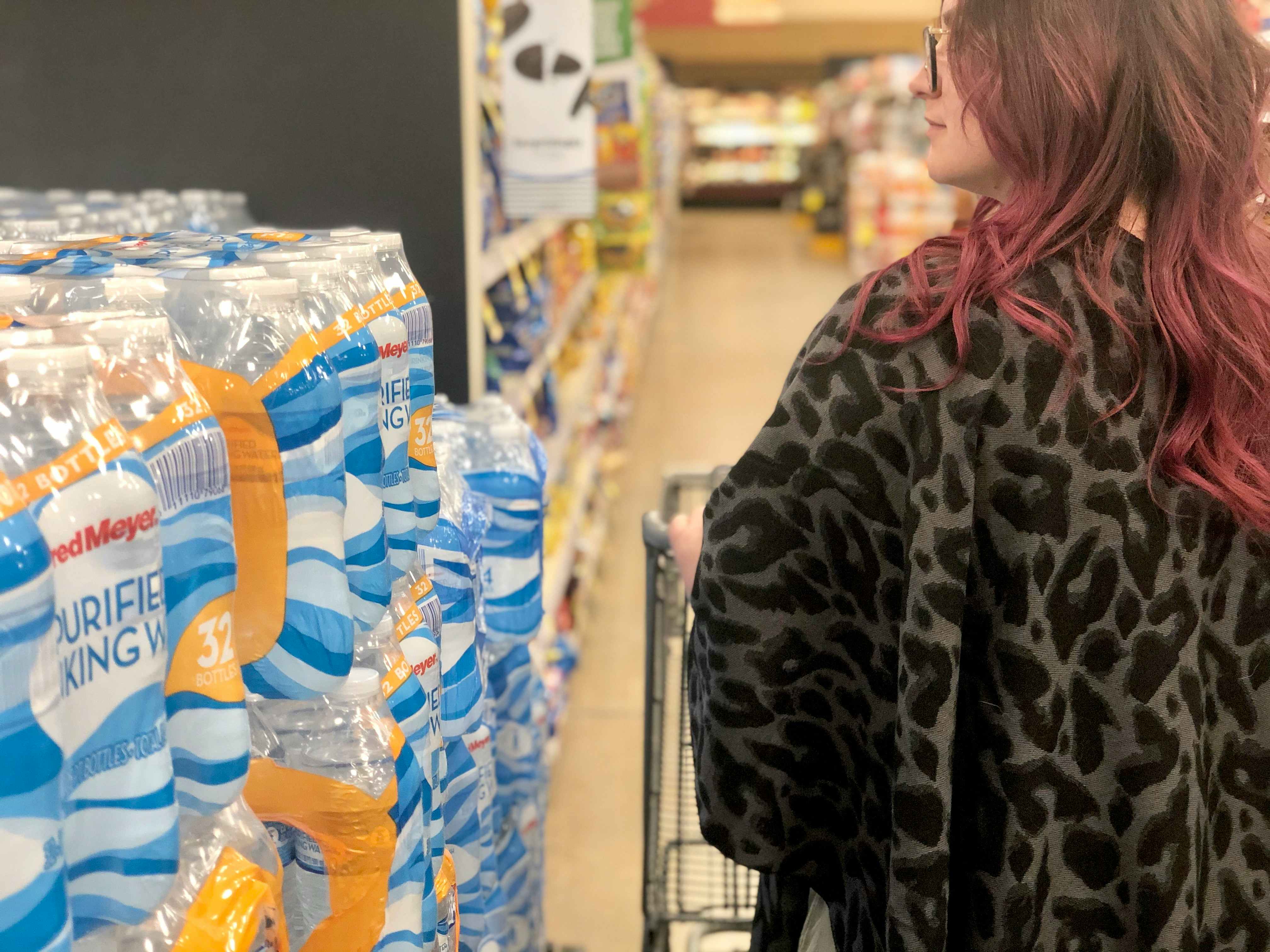 A woman passes by plastic water bottles at the store.