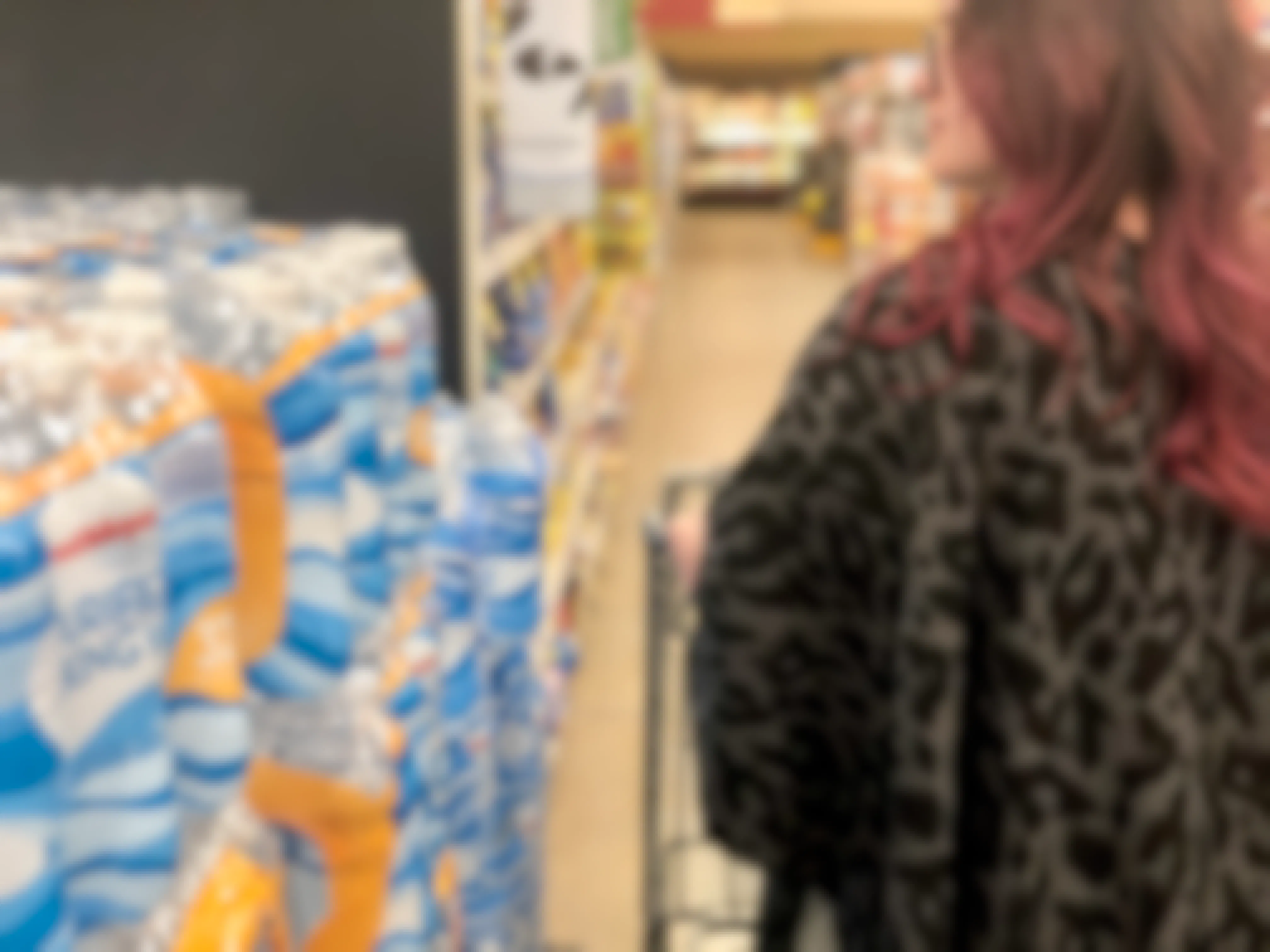 A woman passes by plastic water bottles at the store.